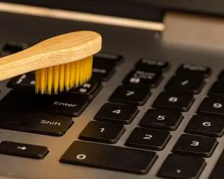 pulire la tastiera di un laptop con una spazzola