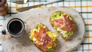 Bacon crocante em cima de ovos mexidos e torradas de abacate com café preto