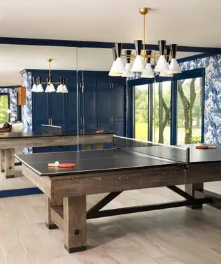 herna se stolem na stolní tenis, modrá skříň, modrá tapeta, retro závěsné světlo, skleněné dveře do zahrady, zrcadlová stěna