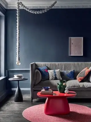 Grå stuevegger med grå sofa og rødt salongbord