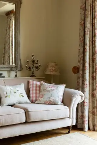 Stue med tradisjonell beige sofa med rullearmer og blomstergardiner