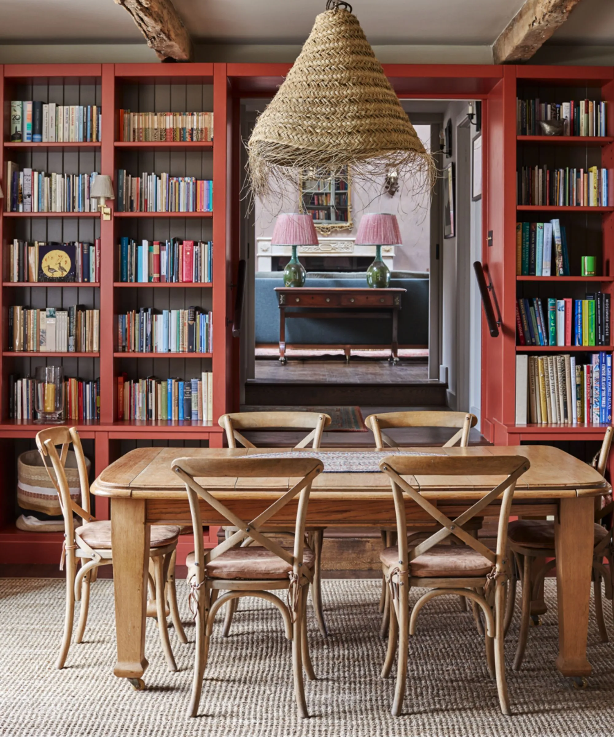 Tavolo da pranzo in legno con librerie dipinte rosse sullo sfondo' loading='lazy' title=