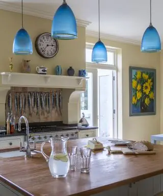Cozinha amarela com luminárias azuis suspensas