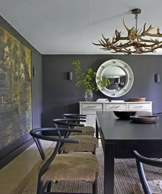 sala de jantar com paredes cinza escuro, lustre de chifre, mesa e cadeiras pretas