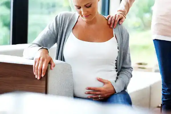 Pregnant Woman Holding Belly And Contemplating The Chances of Down Syndrome