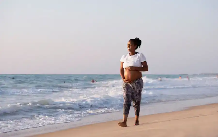 Pregnant woman walking on the beach