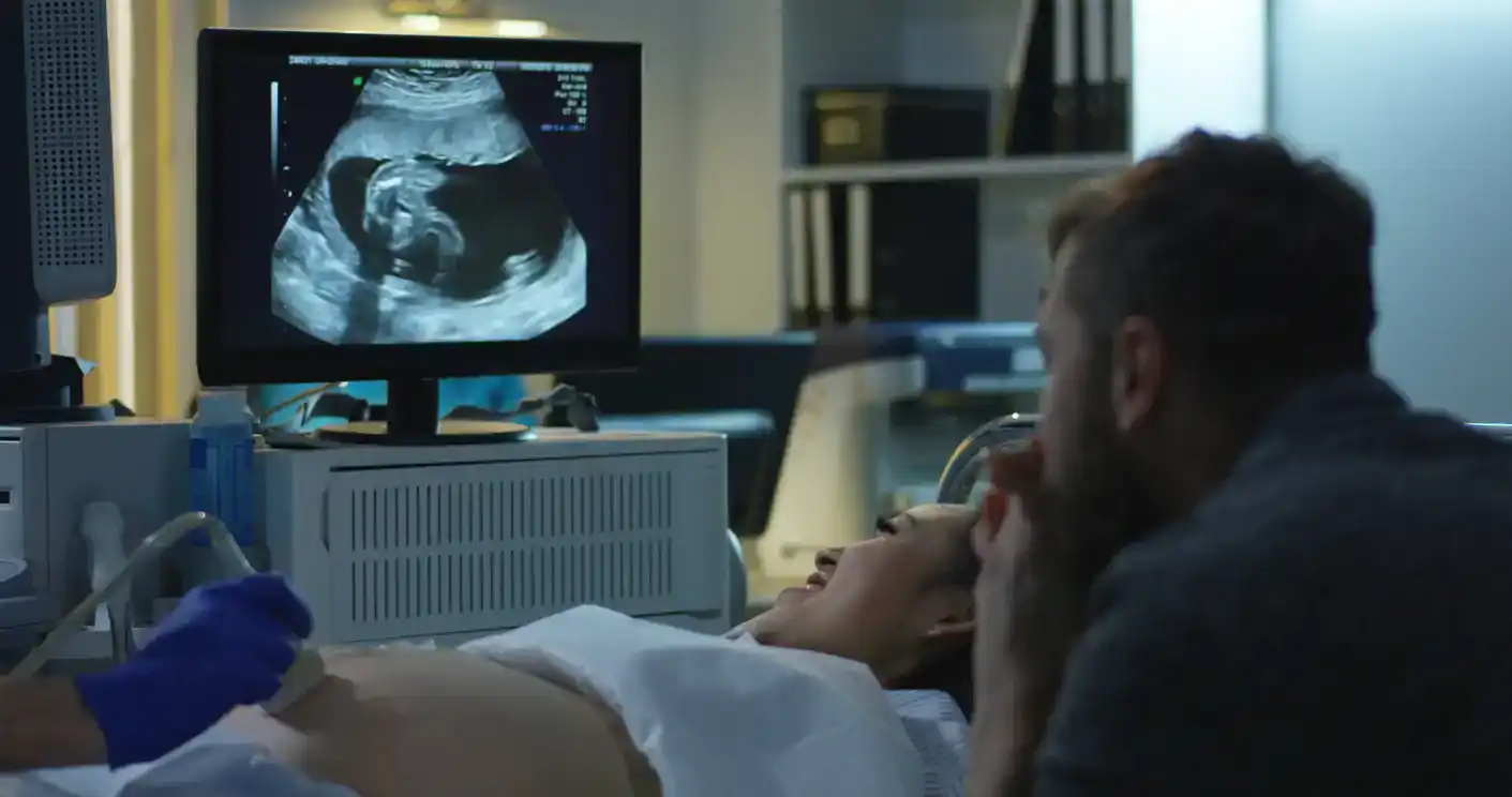 Medium close-up of a young couple watching ultrasound image of future child during ultrasound scan