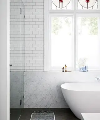 łazienka z białymi płytkami metra, marmurem z Carrary i wolnostojącą wanną zaprojektowaną przez Sarah McPhee w zabytkowym domu w Melbourne