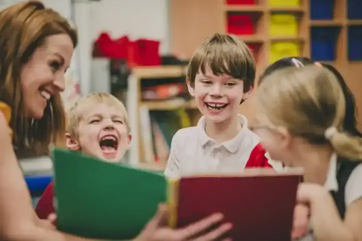 Teacher reads picture book aloud to class, class laughs