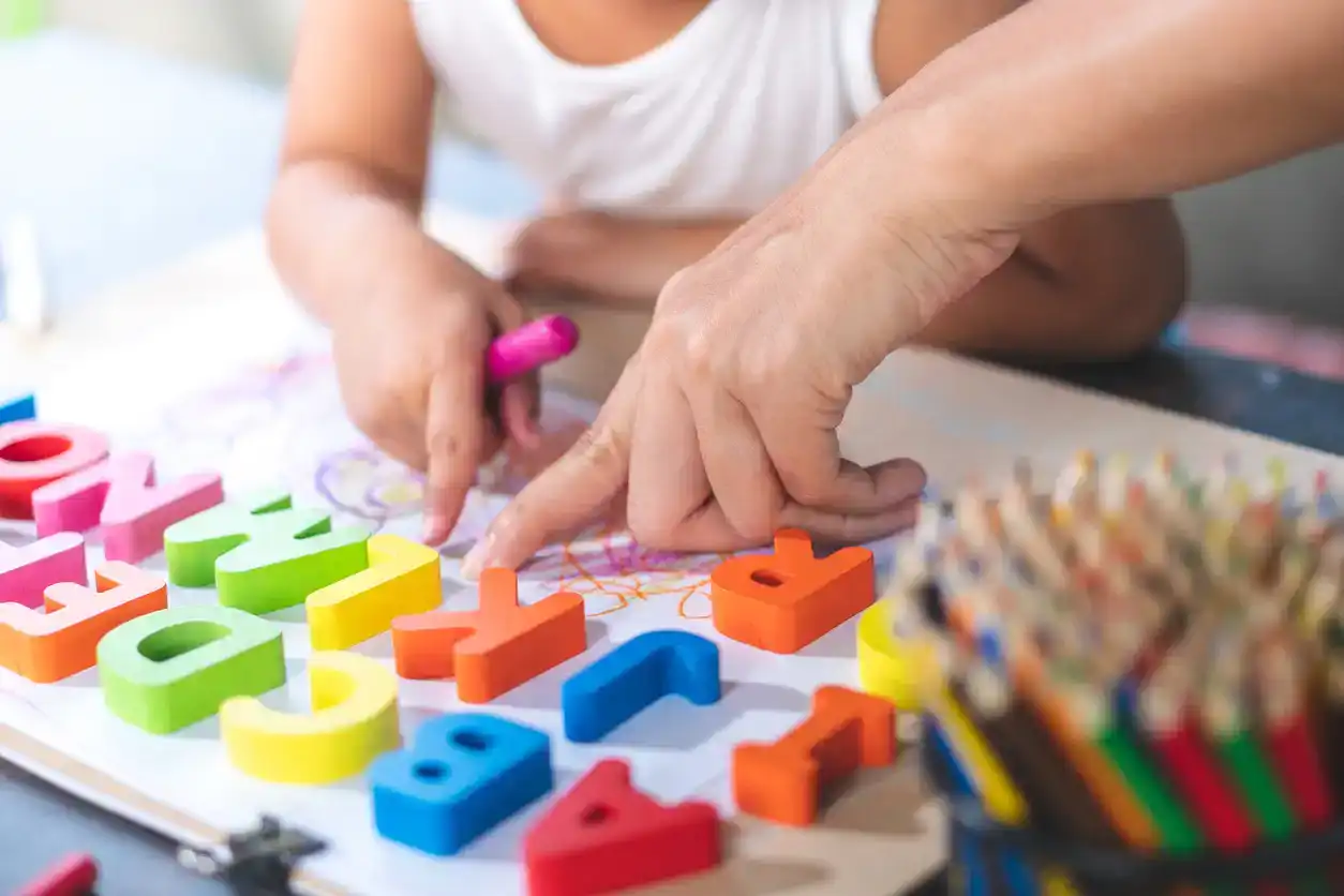 little girl is learning English letters using blocks