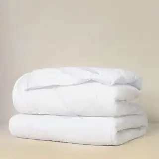 Plys madrasbeskytter mod en beige baggrund.