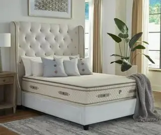 Materasso in lattice organico PlushBeds Botanical Bliss su un letto contro un muro bianco.