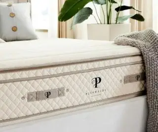 Angolo di un materasso in lattice organico PlushBeds Botanical Bliss, ricoperto da una coperta grigia.