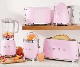 Un grille-pain, une bouilloire, un presse-agrumes et un mixeur roses sur un comptoir