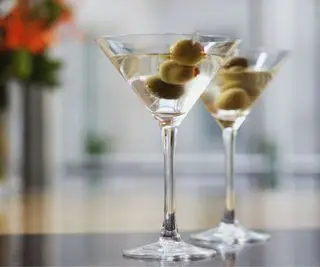 Kieliszek do martini z oliwkami i kwiatami w tle