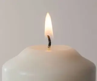 흰 벽 앞의 창백한 촛불에 있는 촛불 심지