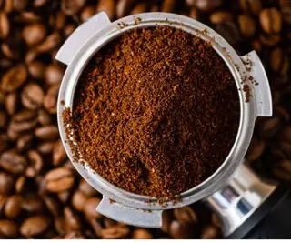 kaffegrut i et portafilter på toppen av kaffebønner