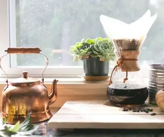drypp kaffetrakter på en vinduskarm med en kobberkjele