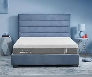 Le matelas Tempur-Pedic ProAdapt contre un mur bleu.