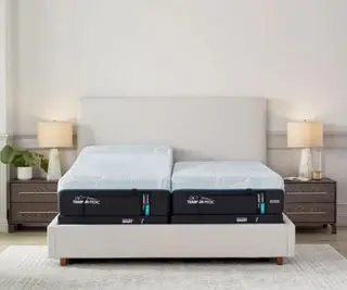 Le matelas Tempur-Pedic ProAdapt sur un lit contre un mur blanc.