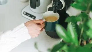 Le macchine da caffè sono tossiche? due macchine da caffè a cialde con sotto una mano che tiene una tazza di caffè