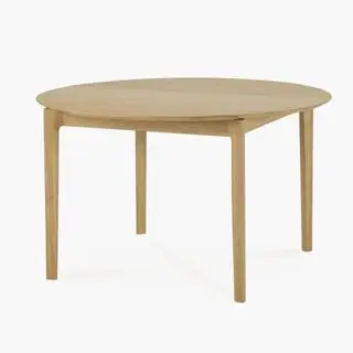 Un tavolo da pranzo rotondo in legno chiaro su sfondo bianco