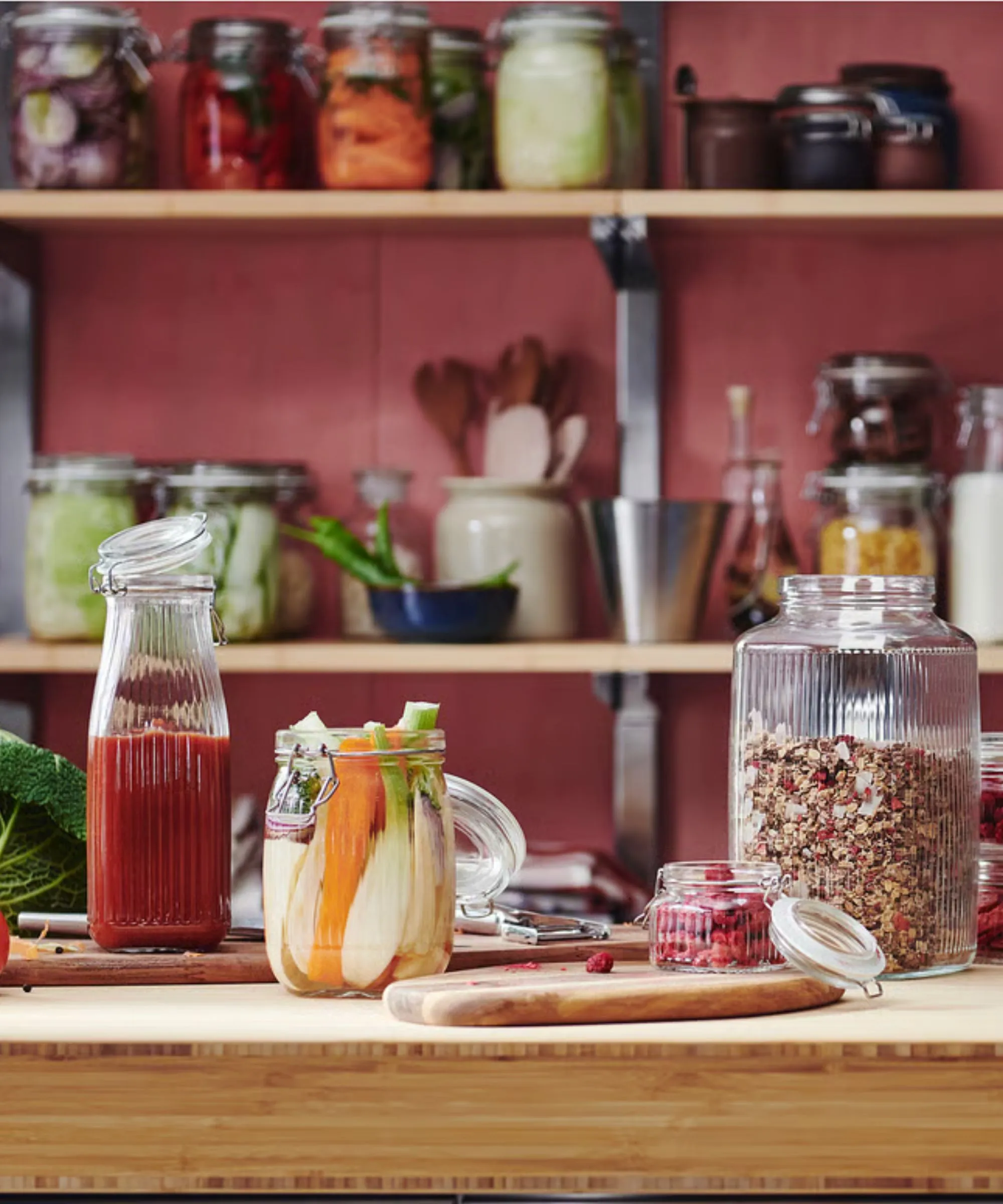 Cucina rosso ciliegia con credenza in legno che espone barattoli per la conservazione degli alimenti in vetro scanalato' loading='lazy' title=