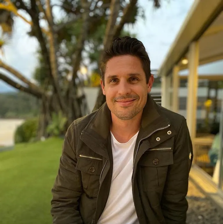 Foto do perfil de Josh Mitchell em um quintal ensolarado com palmeiras em um fundo desfocado' loading='lazy' title=
