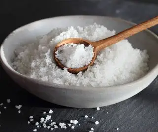 Uma tigela branca de sal com uma colher