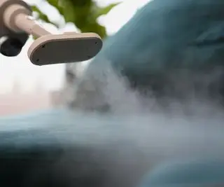 Alguém usando um limpador a vapor nas almofadas do sofá