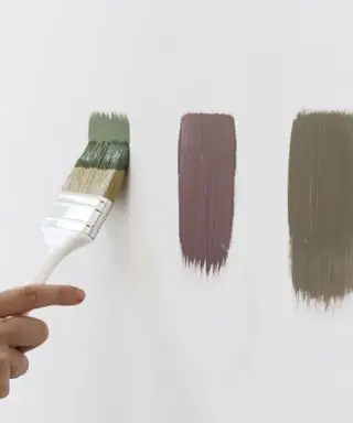 Někdo maluje na zeď proužky vzorků barev