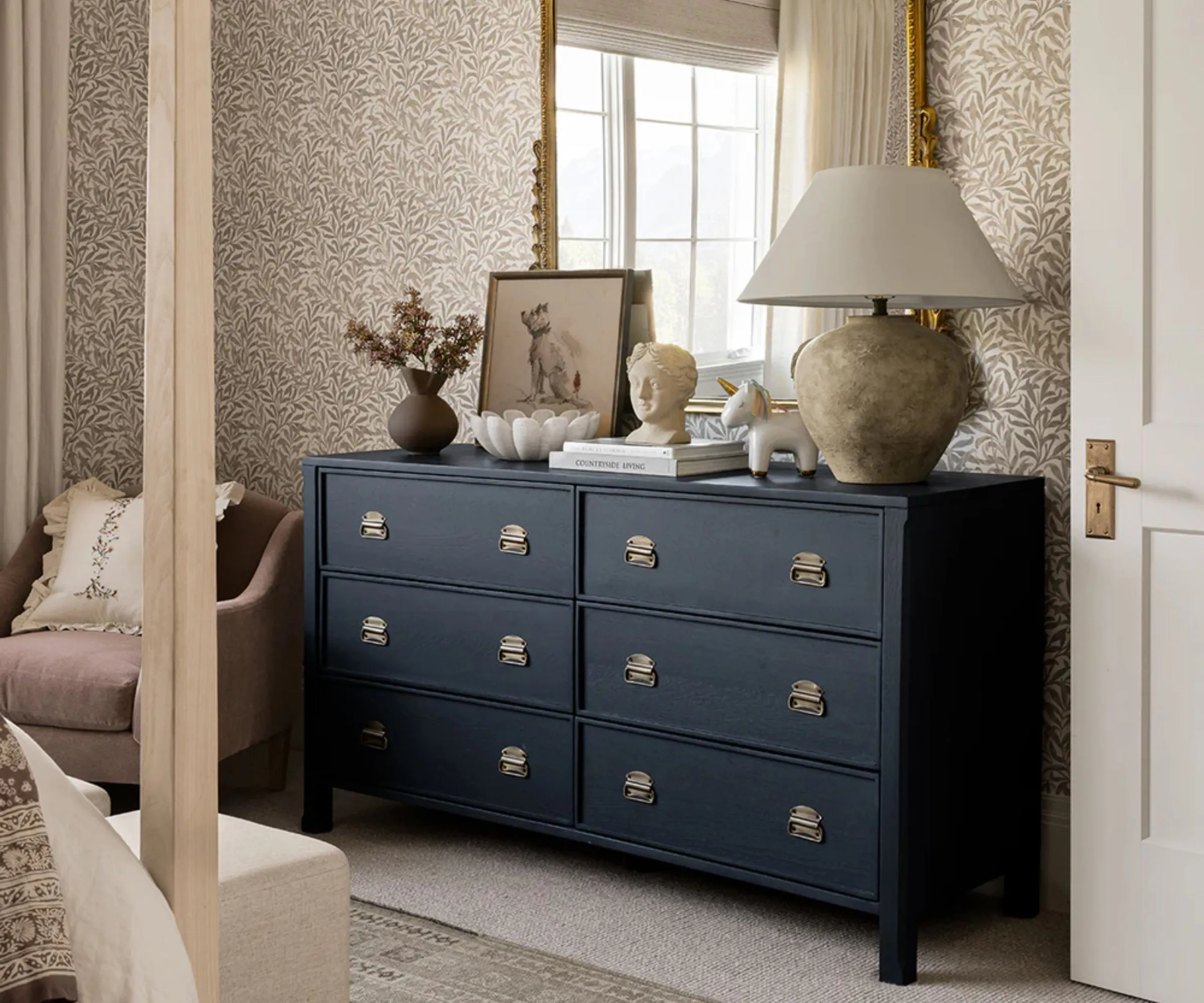 Uma cômoda de 6 gavetas pintada de azul escuro em um quarto.' loading='lazy' title=