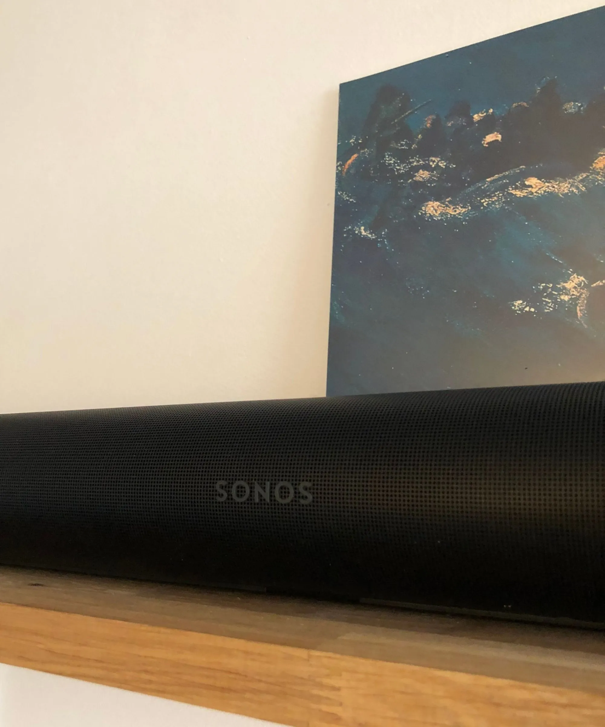 Barra de som Sonos Arc Ultra em uma prateleira de madeira em frente à capa de vinil de Since I Left You do The Avalanches e parede branca.' loading='lazy' title=