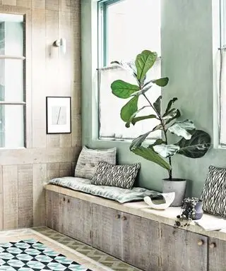 banc de fenêtre avec coussins et grande plante d'intérieur