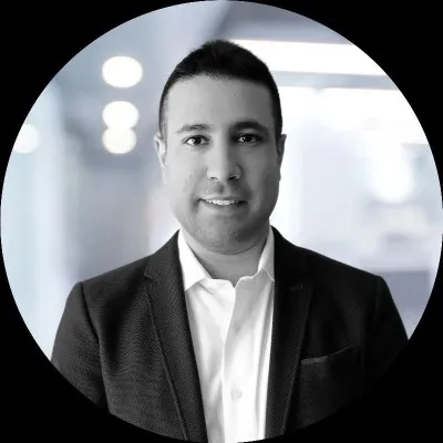 Eli est un homme aux cheveux courts illustré en noir et blanc portant une chemise blanche à col et une veste de costume noir' loading='lazy' title=