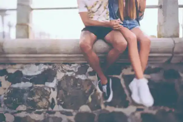 teen couple sitting on rock wall