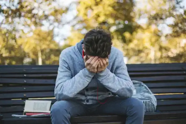 depressed teen boy on bench outside