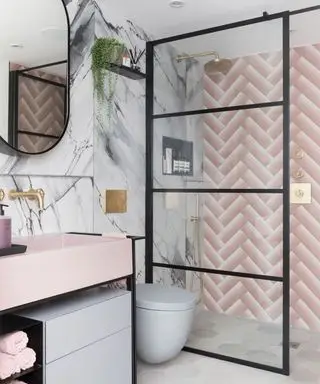 Rosa Wandfliesen mit Fischgrätenmuster und eine graue Marmorwand in einer Dusche