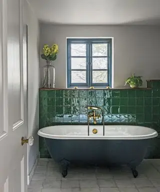 Kräftige grüne Wandfliesen hinter einer dunkelgrünen freistehenden Badewanne