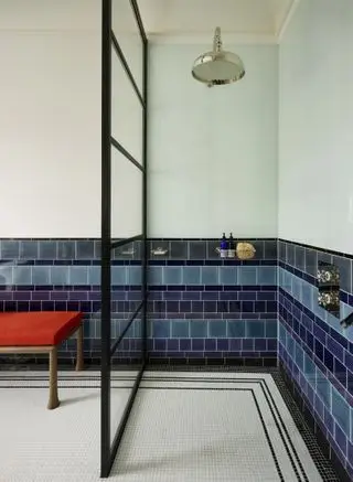 box amplo com azulejos azuis e brancos, porta de vidro, armazenamento, chuveiro de latão