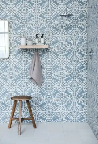 azulejos estampados azuis no chuveiro, piso azul, espelho, prateleira e banquinho