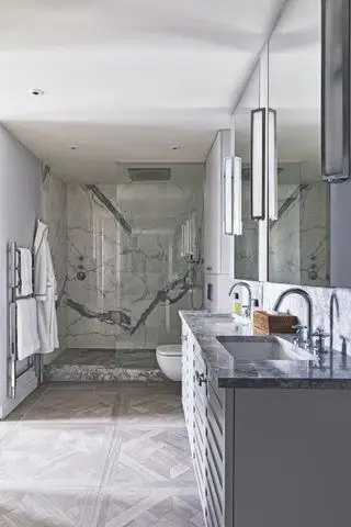 Chuveiro amplo com piso em parquet, bancada de mármore cinza na penteadeira, espelhos, portas de box de vidro