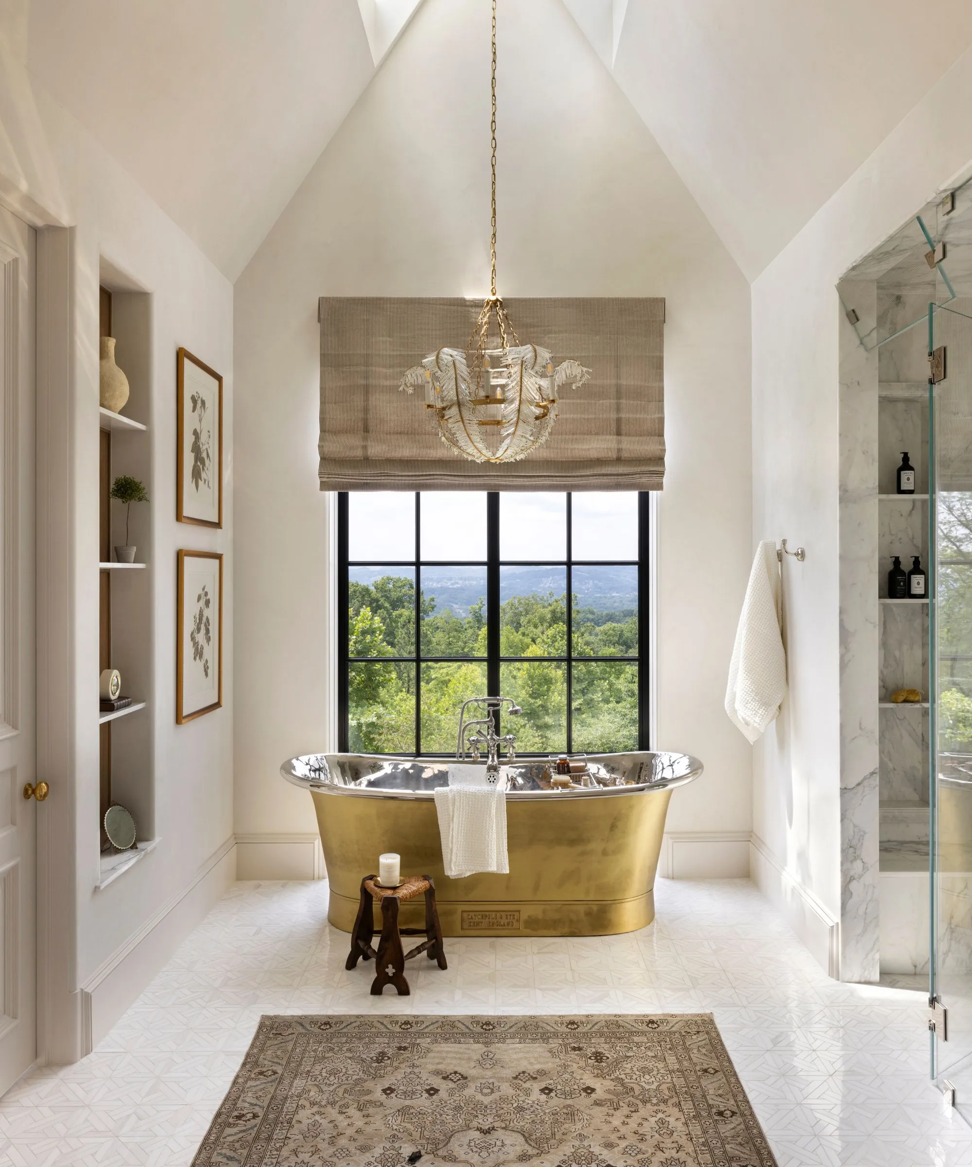 Bílá volně stojící vana v koupelně se světlými dlaždicemi spárovaná s vnitřním stromem a rustikální bílou stoličkou' loading='lazy' title=