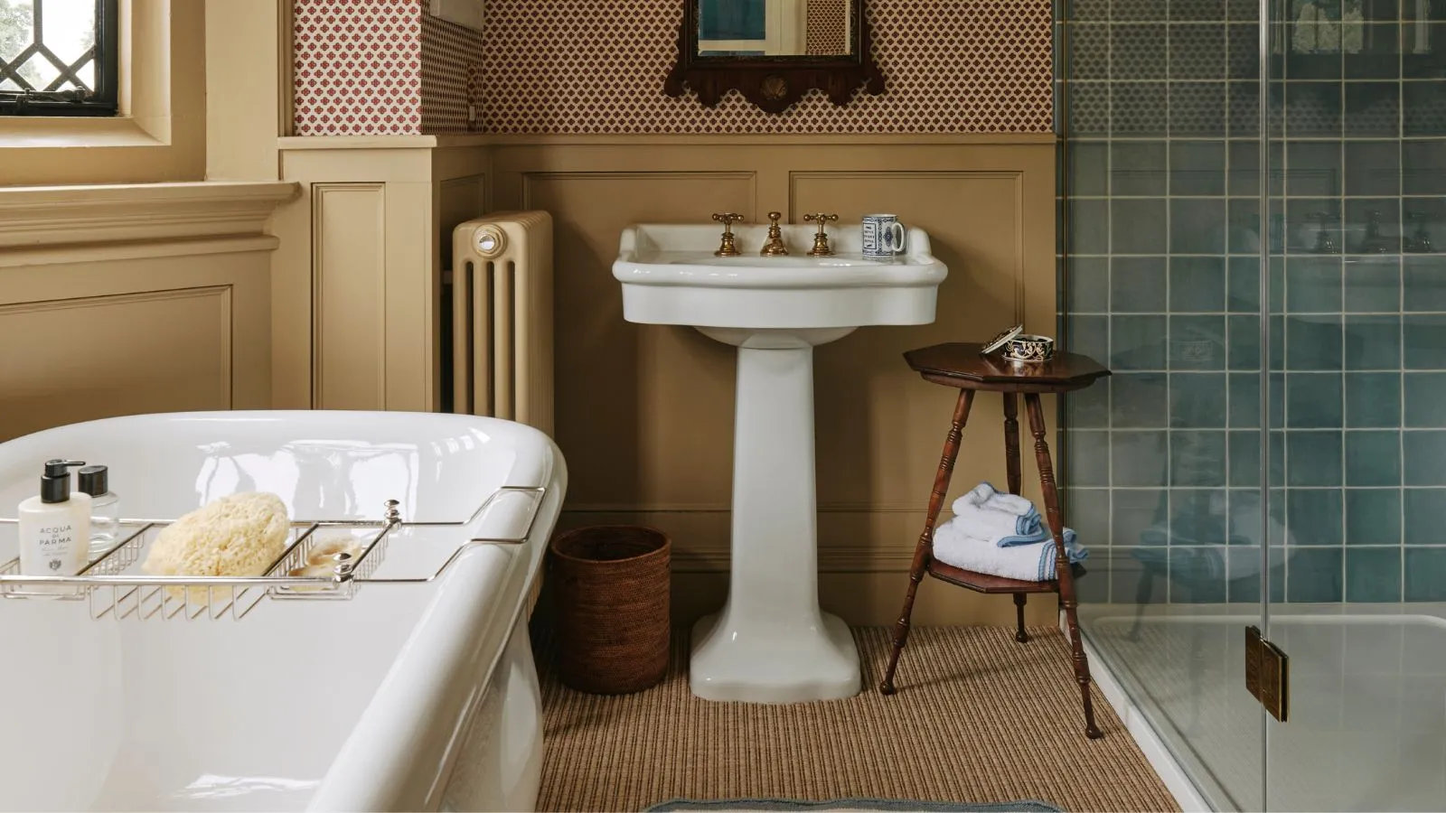 Koupelna s máslově žlutým obložením podstavce umyvadlo modré kachličky sprchový dřevěný odkládací stolek a vana s věšákem' loading='lazy' title=