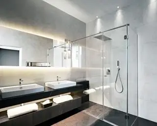 Moderní koupelna s LED páskovým osvětlením nad zrcadlem, sprchovým koutem s bodovými světly, světle šedými obklady, tmavě šedými obklady, černým umyvadlem s dvojitým umyvadlem