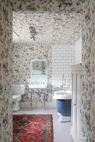 Cuarto de baño con papel tapiz de Charlotte Gaisford y alfombra antigua