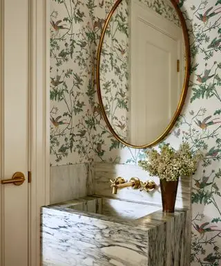banheiro pequeno com pia de mármore e papel de parede floral