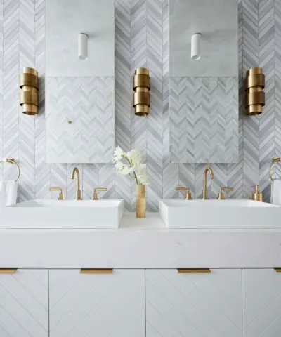 Bagno ampio e moderno con soffitto con pannelli in legno, lampadario moderno in metallo e vetro, piastrelle in marmo su una parete, grande vasca bianca, mobile lavabo da parete a parete con cassetti in legno, piano di lavoro in marmo, grande specchio rotondo sopra i lavandini, pavimento in marmo, parete strutturata verde , sgabello in legno a forma di mano accanto alla vasca