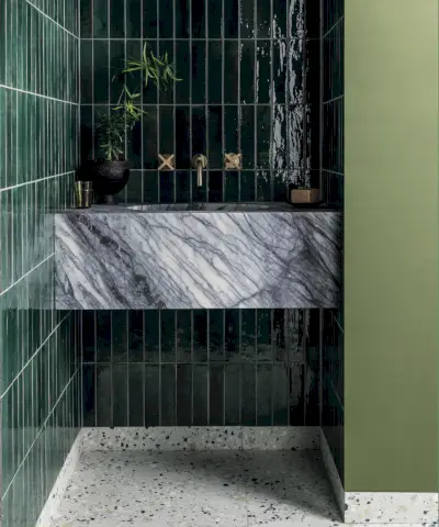 Bagno a tema pastello, piastrelle geometriche blu e bianche, mix di diverse forme e colori di piastrelle sulle pareti, pareti dipinte in una gamma di colori pastello, grande mobiletto bianco con doppi lavandini e specchi ad arco, applique su specchi, vasca da bagno rosa