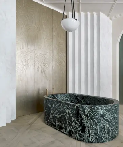 Bagno verde brillante con pavimento e rivestimenti verdi in stile marocchino, pareti verniciate di verde strutturato, specchio arrotondato con applique in vetro sul lato etere, lavabo tradizionale con lavandini bianchi e ripiano inferiore bianco, elementi metallici in ottone